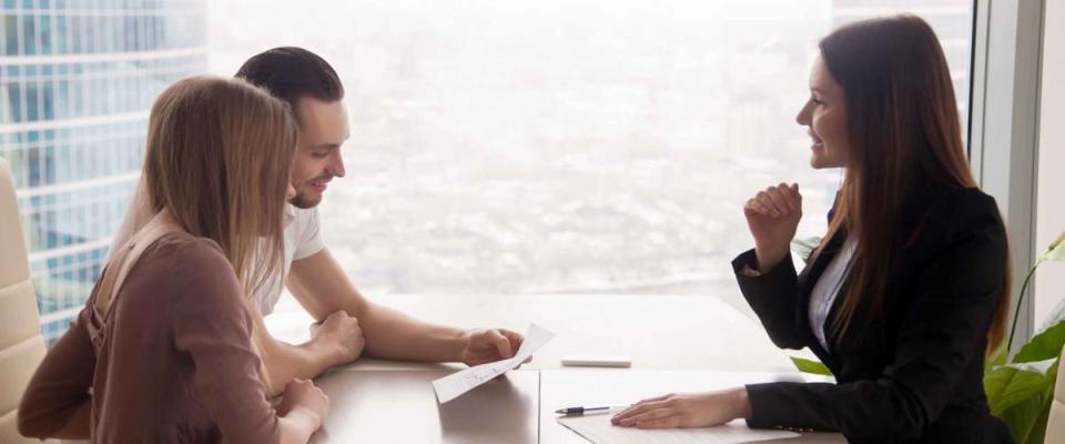 Side view of woman in suit talking to couple across a table