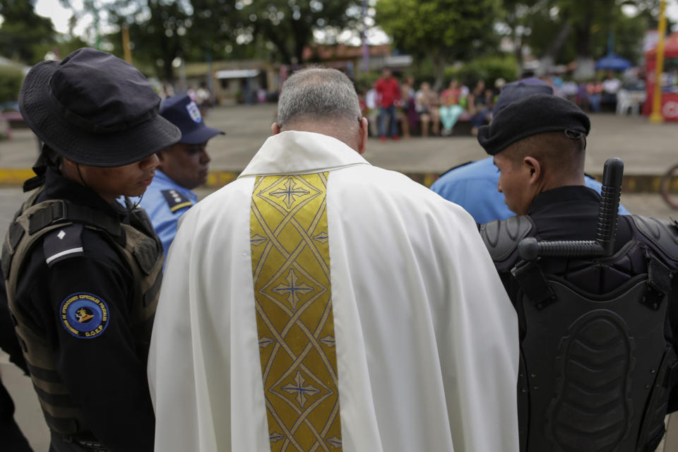 Father Edwin Roman attempts to convince the police to allow relatives of imprisoned and dead anti-government demonstrators to enter the San Miguel Arcangel Church in Masaya, Nicaragua, Thursday, Nov. 14, 2019. The relatives have started a hunger strike to demand the freedom of their relatives, jailed for protesting against the government of President Daniel Ortega. (AP Photo/Alfredo Zuniga)