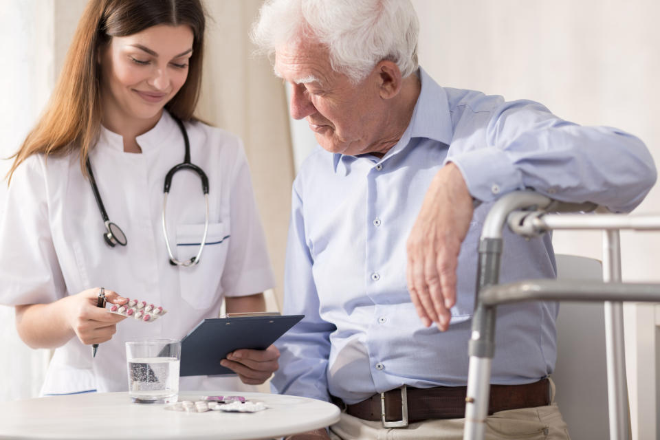 Nurse giving medication to elderly man.