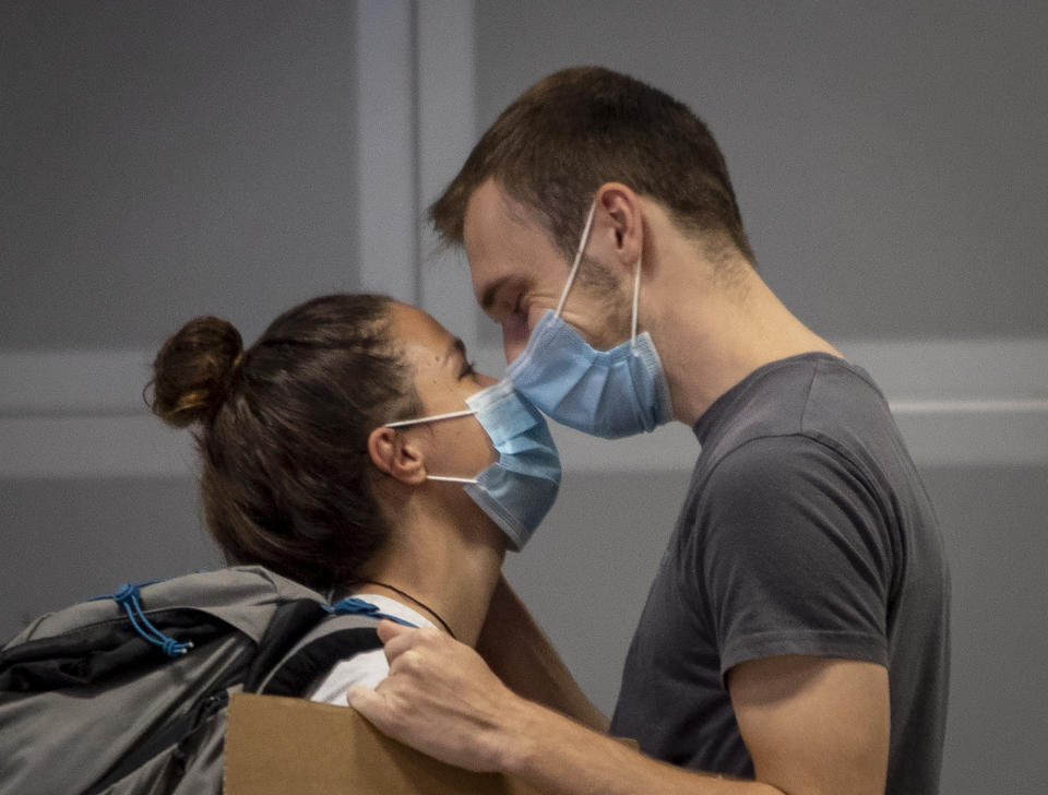 A young man welcomes his girl friend arriving from Singapore at the airport in Frankfurt, Germany, Saturday, Aug. 8, 2020. From Saturday on Covid-19 tests are mandatory for passengers coming from a high-risk-country. (AP Photo/Michael Probst)