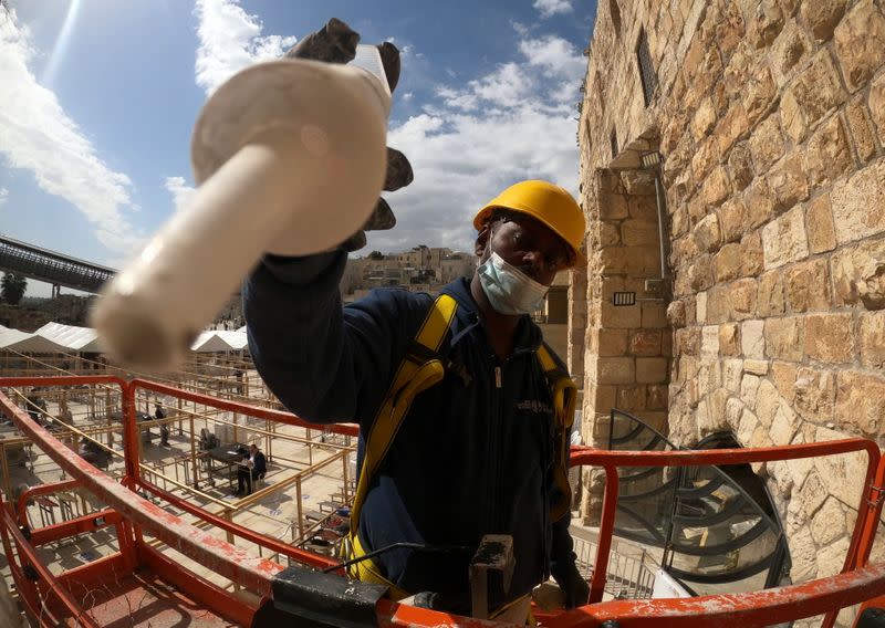 A labourer stands on a portable lift as he injects a type of grout into gaps and fissures in the stones of the Western Wall, Judaism's holiest prayer site, as part of the Israel Antiquities Authority treatment of the ancient stones, in Jerusalem's Old City