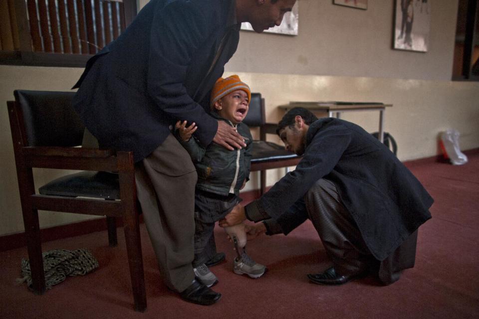 In this Friday, Jan. 17, 2014 photo, a Pakistani child cries from pain while a therapist applies on his artifical limb at the Armed Forces Institute for Rehabilitation Medicine in Rawalpindi, Pakistan. Soldiers of the Pakistani security forces learn exactly these types of scenarios to deal with the improvised bombs that have become increasingly popular in wars like Iraq, Afghanistan and the insurgency that Pakistan's forces are fighting in the northwestern tribal areas. (AP Photo/Muhammed Muheisen)