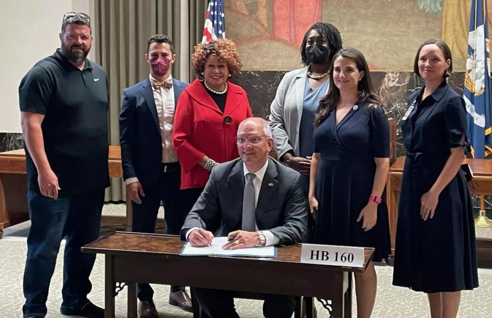 Gov. John Bel Edwards signs House Bill 160 on Thursday, August 4, 2022, surrounded by advocates and the measure's legislative sponsor.