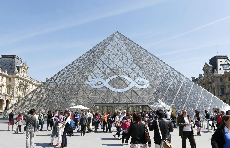 Italian artist Michelangelo Pistoletto's art work decorates the Louvre museum's iconic glass pyramid, in Paris, Wednesday, April 24, 2013. Michelangelo Pistoletto, one of the world's leading conceptual artists, covered one panel of the pyramid with a huge three-looped infinity sign made of mirrors Wednesday. It’s an artistic gesture aimed to show politicians and society the follies of excess that led to the current financial crisis. (AP Photo/Jacques Brinon)