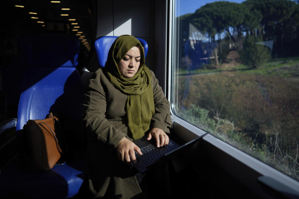 Batool Haidari, 37 works at her laptop on a train taking her from her home on the outskirts of Rome, to the capital's center, Monday, Dec. 5, 2022. Batool Haidari was a prominent professor of sexology at a university in Kabul before last year’s Taliban takeover of Afghanistan. She used to lecture mixed classes of male and female students and look after her patients struggling with their gender identity. That comfortable life came to an abrupt halt on Aug. 15, 2021, when the ultra-religious group swept back into power. (AP Photo/Andrew Medichini)