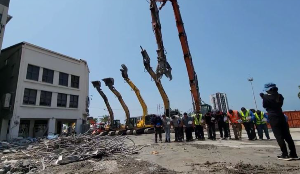 台灣花蓮地震丨工程人員今日上午將5部重型機械朝大樓位置一字排開，脫下工程帽向罹難的女教師致意。(網上圖片)