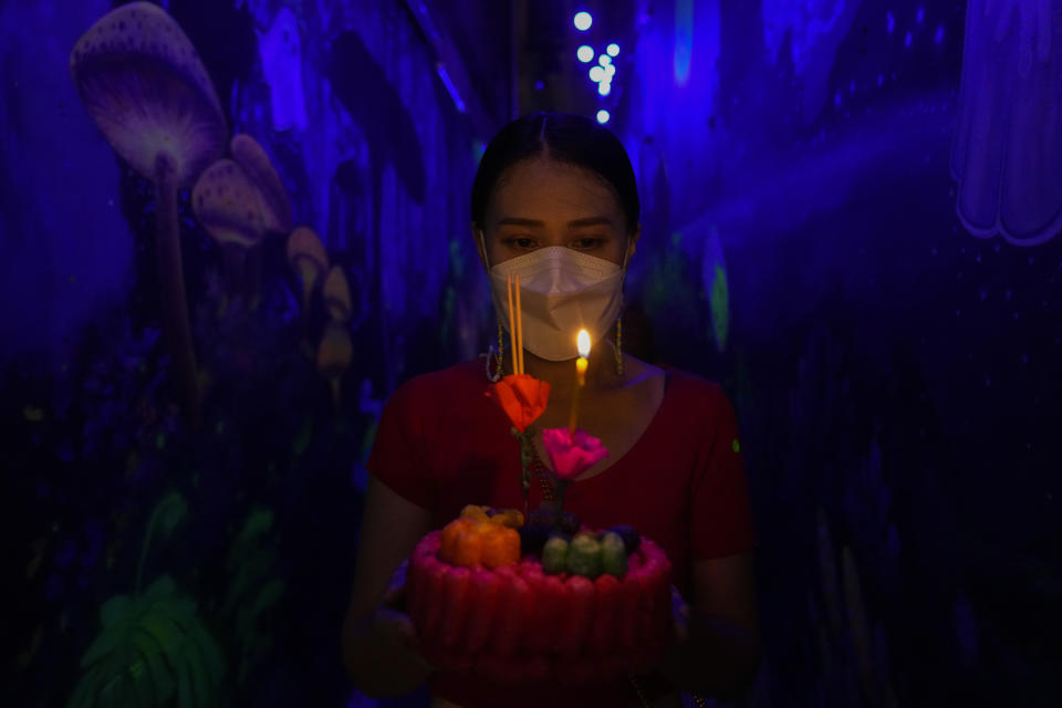 A Thai woman prays before floating a krathong, a small boat made of corn and decorated with banana leaves and flowers, into a Ong Ang canal during Loy Krathong festival in Bangkok, Thailand, Friday, Nov. 19, 2021. Thais believe that the candle-lit boats launched during the charming and popular Loy Krathong festival can carry the year's misfortunes away with them, but workers must clean up the waterways afterward to keep them from getting clogged and polluted. (AP Photo/Sakchai Lalit)