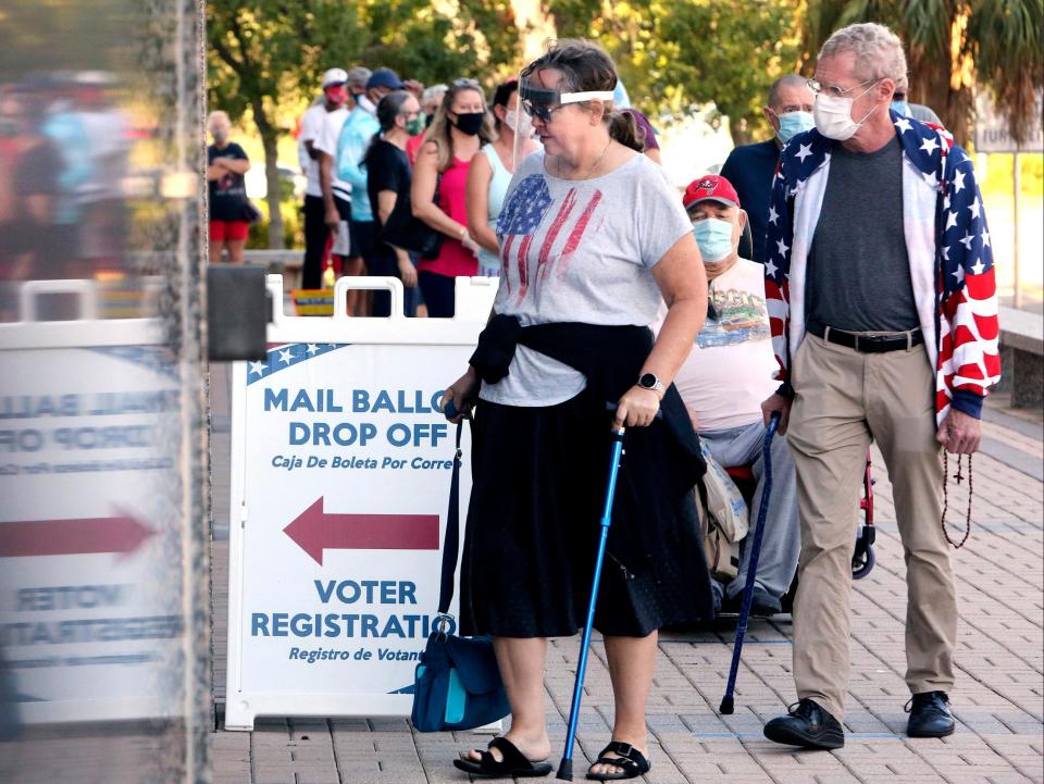 Voters Jenny Hart, center, and James Hart, of Clearwater, wait in line to enter the Supervisor of Elections Office at the Pinellas County Courthouse during early voting in Clearwater, Florida, on Monday 19 October ((Associated Press))