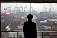 An employee views the Port of Shanghai from an office window