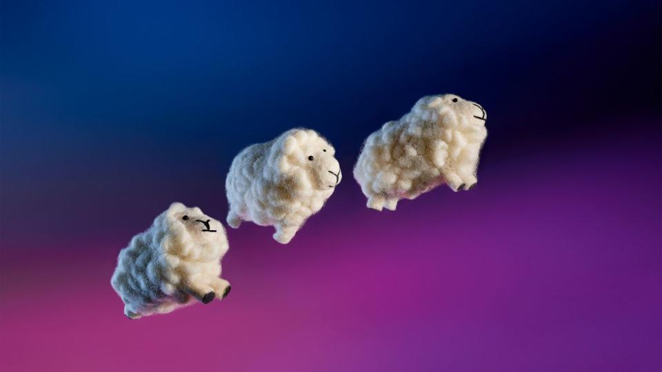 three wool sheep toys jumping through the air with a night sky background