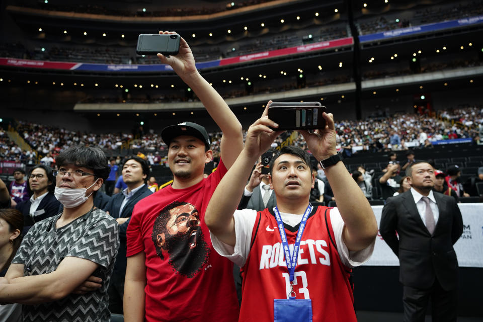 Fans take pictures as players warm up before an NBA preseason basketball game between the Houston Rockets and the Toronto Raptors Tuesday, Oct. 8, 2019, in Saitama, near Tokyo. (AP Photo/Jae C. Hong)