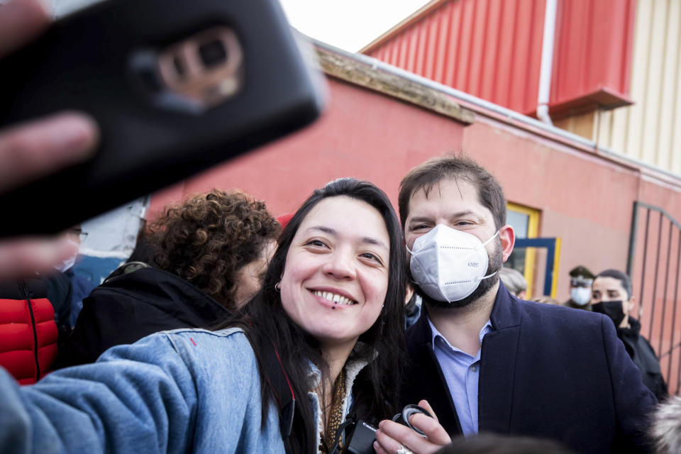 Chile's President Gabriel Boric poses for a picture with a supporter outside a polling station before casting his vote in a plebiscite on a new draft of the Constitution in Punta Arenas, Chile, Sunday, Sept. 4, 2022. Chileans are deciding if they will replace the current Magna Carta imposed by a military dictatorship 41 years ago. (AP Photo/Andres Poblete)