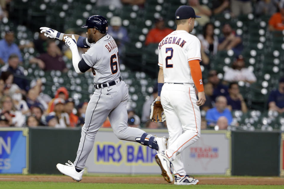 Detroit Tigers' Akil Baddoo, left, points to the stands as he crosses Houston Astros third baseman Alex Bregman, right, as he rounds the bases on his home run during the third inning of a baseball game Monday, April 12, 2021, in Houston. (AP Photo/Michael Wyke)