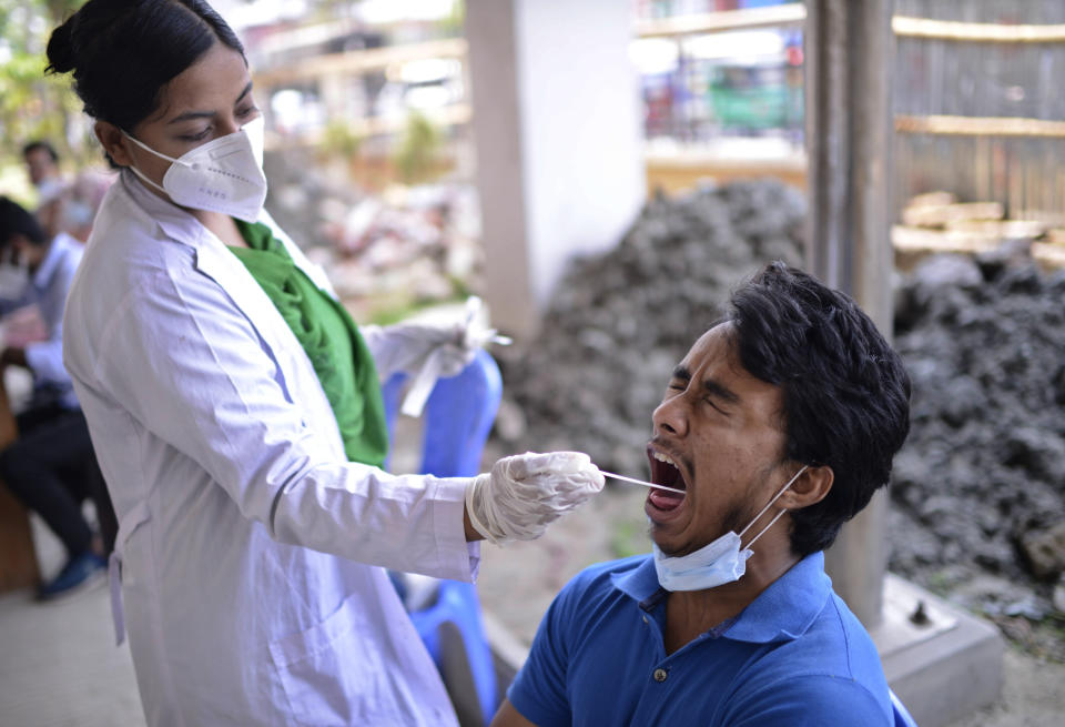 A Bangladeshi health worker takes a mouth swab sample of a man to test for COVID-19 in Dhaka, Bangladesh, Saturday, May 8, 2021. India's surge in coronavirus cases is having a dangerous effect on neighboring Bangladesh. Health experts warn of imminent vaccine shortages just as the country should be stepping up its vaccination drive, and as more contagious virus variants are beginning to be detected. (AP Photo/Mahmud Hossain Opu)