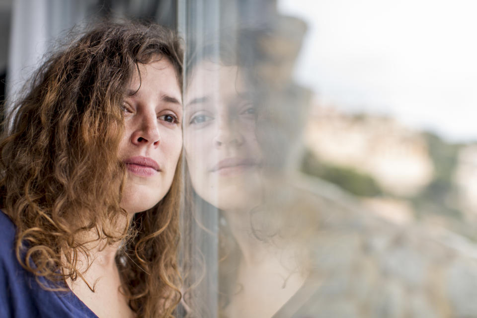 Woman looking sadly out of window as if in grief