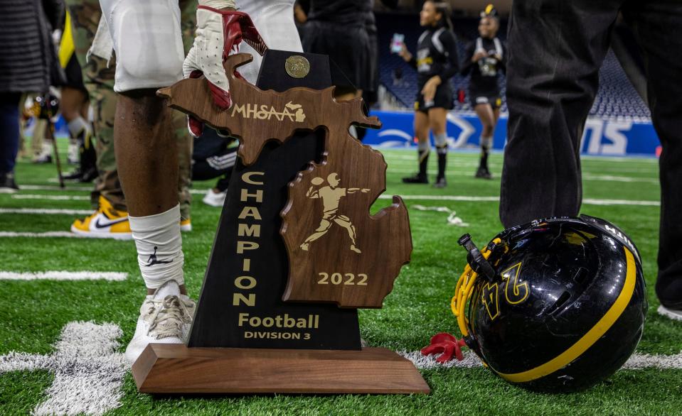 Detroit King's  Tim Ruffin (24) picks up the trophy after a 56-27 victory against Muskegon during the Division 3 high school football finals at Ford Field in Detroit on Saturday, Nov. 26, 2022.