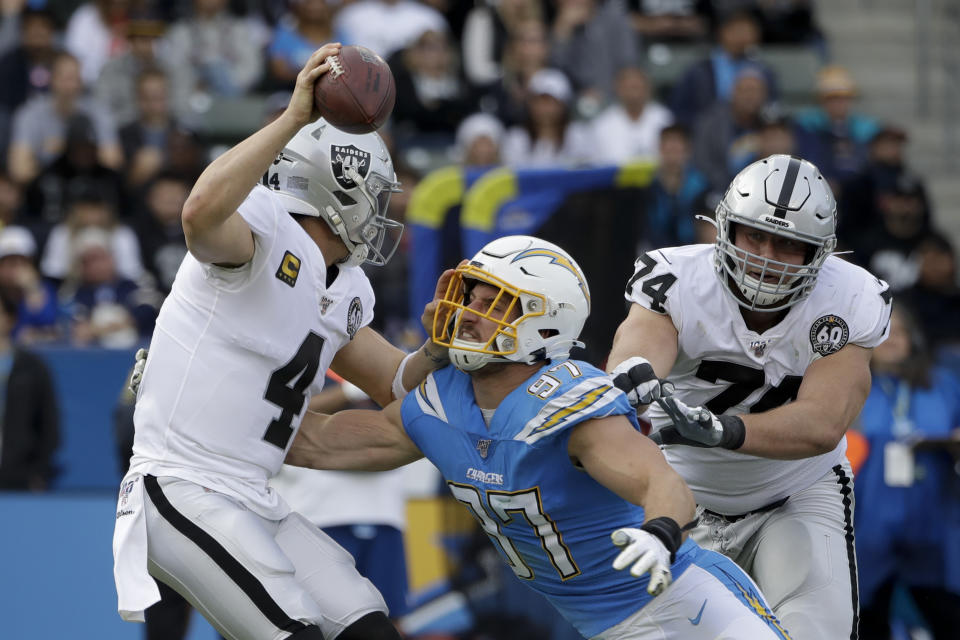 FILE - In this Dec. 22, 2019, file photo, Oakland Raiders quarterback Derek Carr is sacked by Los Angeles Chargers defensive end Joey Bosa during the first half of an NFL football game in Carson, Calif. Teams could afford recent contracts like the megabucks given to Patrick Mahomes and Bosa under normal circumstances. Because of economic effects from the coronavirus pandemic, future player deals and a salary cap that will be adjusted due to some monetary setbacks, upcoming free agents might find the marketplace tighter. (AP Photo/Marcio Jose Sanchez, File)