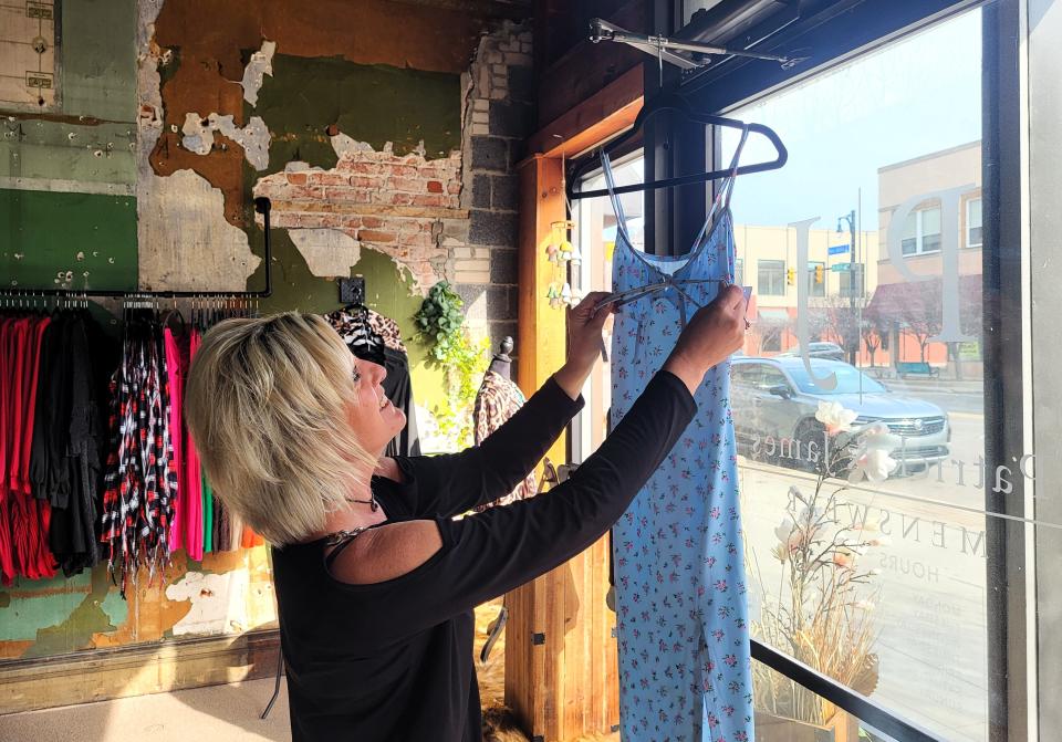 Lori Houle, salon manager at Shear Karma, holds up a sundress on Wednesday, Feb. 21, 2024, at Divine Designs Downtown, where she said she was helping owner Michele Seib set up for the latter business opening within the next few weeks.