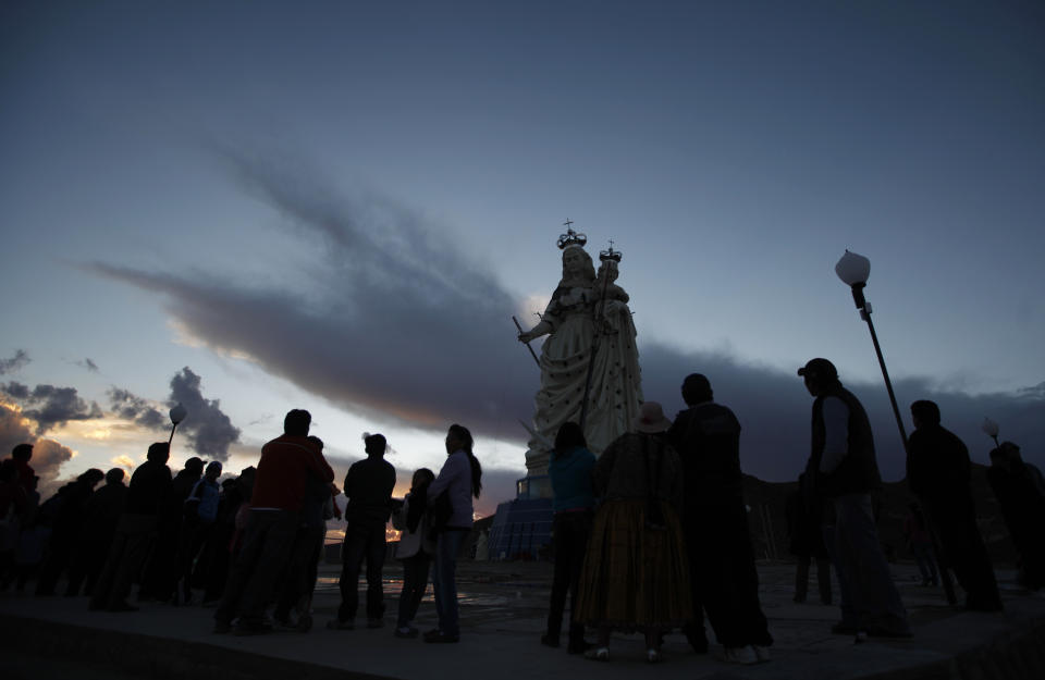 Pilgrims stand at the base of the statue of the Virgin Mary on Santa Barbara hill as the sun begins to rise in the mining city of Oruro, Bolivia, Friday, Feb. 1, 2013. The statue, known in Spanish as "Virgen del Socavón," or the Virgin of the Tunnel, is Oruro's patron, venerated in particular by miners and folkloric Carnival dancers. The statue was unveiled on Friday to mark the start of Carnival in Oruro, which coincides with celebrations honoring the Virgin that starts on Saturday, Bolivia's largest religious event. (AP Photo/Juan Karita)