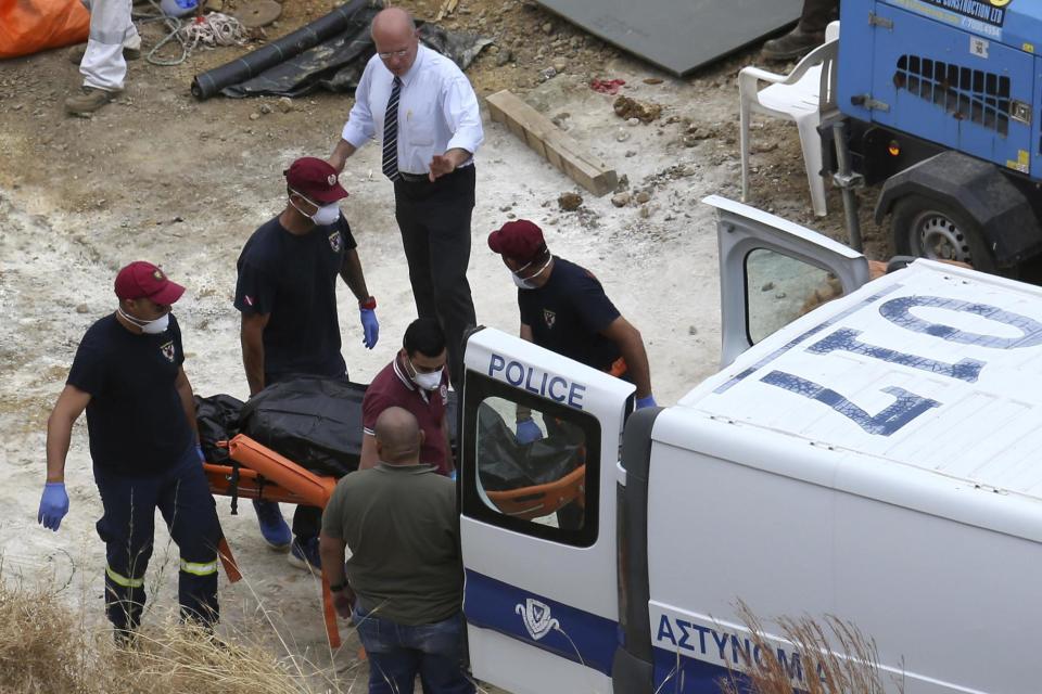 Cyprus' Special Disaster Response Unit investigators carry a covered suitcase on a stretcher after it was retrieved from a man-made lake near the village of Mitsero (AP)