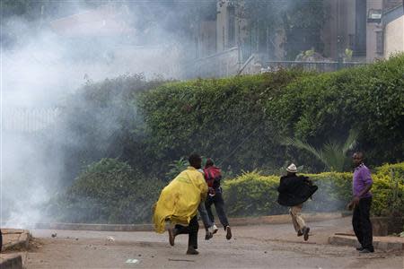 People run from tear gas as security officers (not pictured) disperse a crowd of onlookers near the security perimeter of the Westgate Shopping Centre in Nairobi September 23, 2013. REUTERS/Siegfried Modola