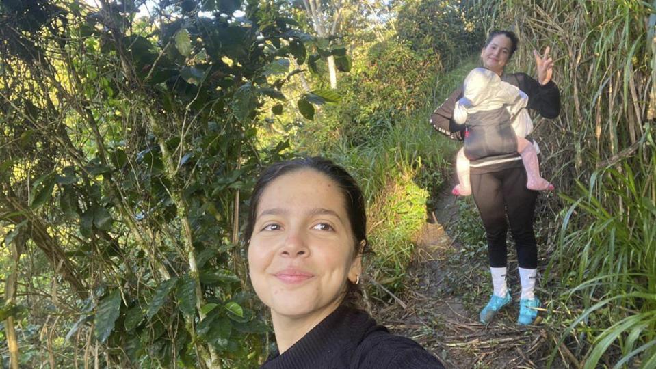In this photo courtesy of Melanie Rolo Gonzalez, she takes a selfie with her sister, Merlyn, in the background carrying her daughter, Madisson, in Nicaragua, early Wednesday, Dec. 14, 2022. The child and two women were winding their way through Central America to migrate to the U.S. Their “guide” was a vague, but constant presence, sending them messages with instructions as they were handed off smuggler to smuggler. (Melanie Rolo Gonzalez via AP)