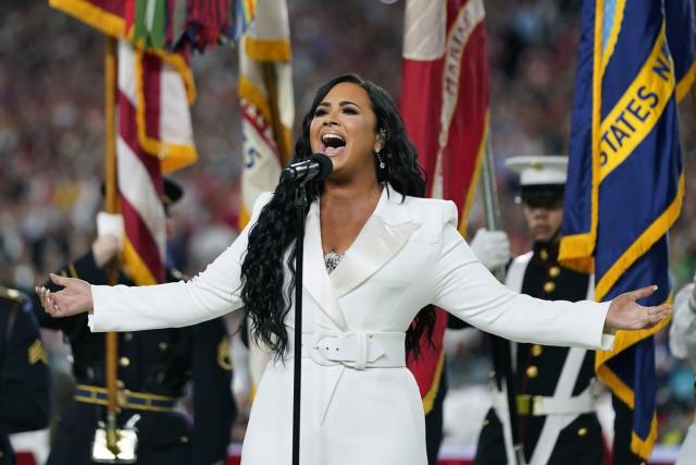 A female singer in a white suit performs in front of military personnel
