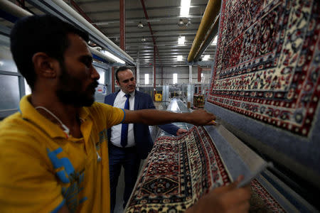Mahmoud Akkad, a carpet manufacturer, stands next to an employee at his carpet factory in Jordan Industrial Estates Company in Al-Muwaqar south of Amman, Jordan, September 14, 2017. Picture taken September 14, 2017. REUTERS/Muhammad Hamed