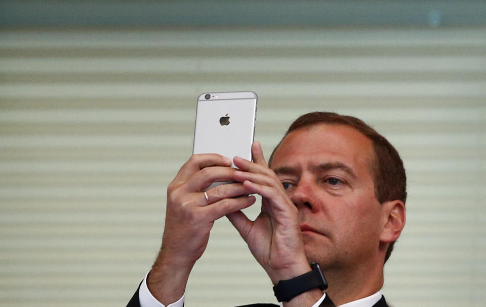 Russian Prime Minister Dmitry Medvedev holds up his smartphone at the Aquatics World Championships in Kazan, Russia, August 9, 2015.      REUTERS/Hannibal Hanschke