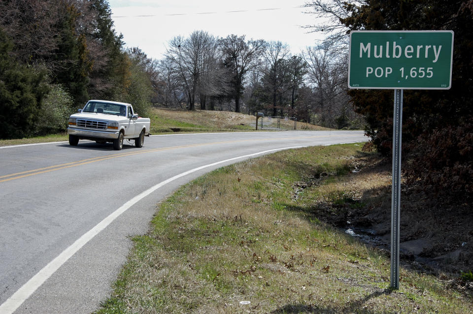 A truck drives near a population sign in Mulberry, Ark., on March 13, 2013. (Jeannie Nuss / AP)