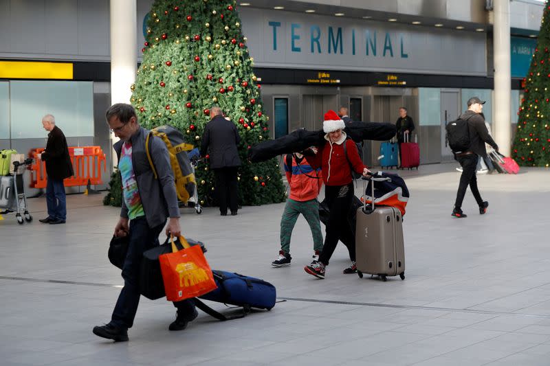 Passengers walk with suitcases in Gatwick Airport, in Crawley