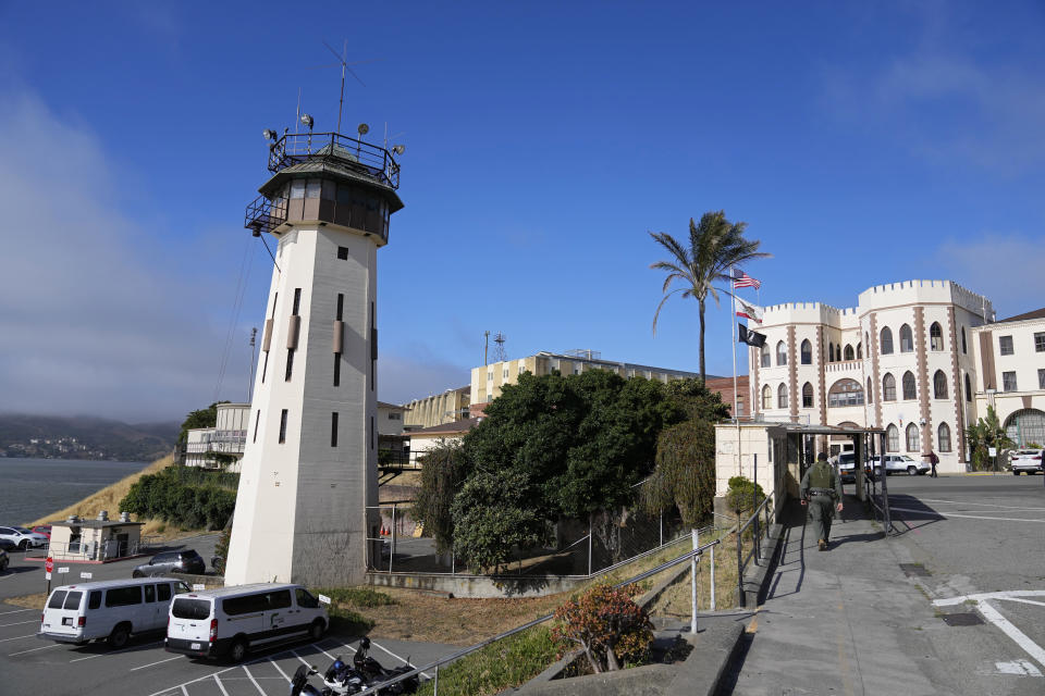 A correctional officer walks up a main entryway at San Quentin State Prison in San Quentin, Calif., on July 26, 2023. California Gov. Gavin Newsom has ambitious and expensive plans for a dilapidated factory at San Quentin State Prison where inmates of one of the nation's most notorious lockups once built furniture. He wants to spend $360 million demolishing the building and replacing it with one more reminiscent of a college campus, with a student union, classrooms and possibly a coffee shop. (AP Photo/Eric Risberg)