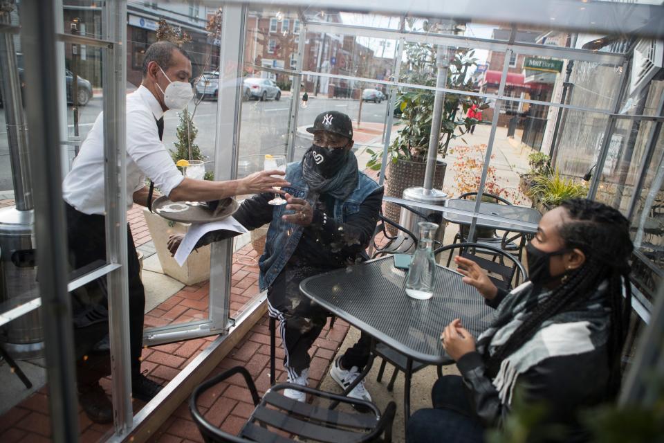 Caffe Gelato lead server Jose Duque serves waters to Arnold Dorsett and Sharee Dorsett at one of the Newark restaurant's outdoor dining greenhouses Monday, Dec. 7, 2020.