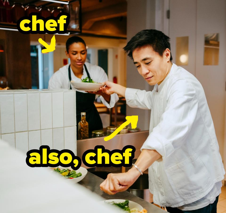 Chefs in a modern kitchen, preparing dishes on plates. A male chef is placing greens on a plate while a female chef places a dish on the counter. Another chef is in the background