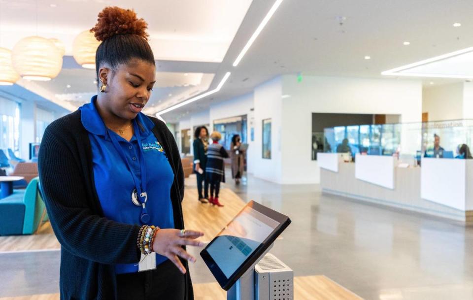 Deja Ross, a Customer Experience Specialist, shows how she will guide visitors through the sign in process so they can get in line for their appointment at the Scarborough Community Resource Center in Charlotte on Wednesday, October 25, 2023.