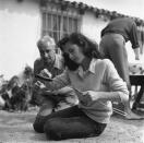 <p>Elizabeth inspects a hot dog she's roasting while at a BBQ. For the event, the actress ditched her normal glam and instead opted for jeans and a cardigan. </p>