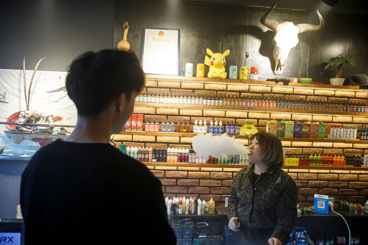 A saleswoman exhales vape as she talks to a customer at the Vape Shop that sells e-cigarette products in Beijing, China, on 30 January, 2019. (Reuters file photo)