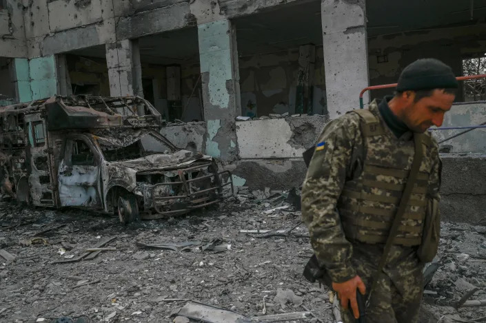 A Ukrainian soldier walks past a school hit by Russian rockets.