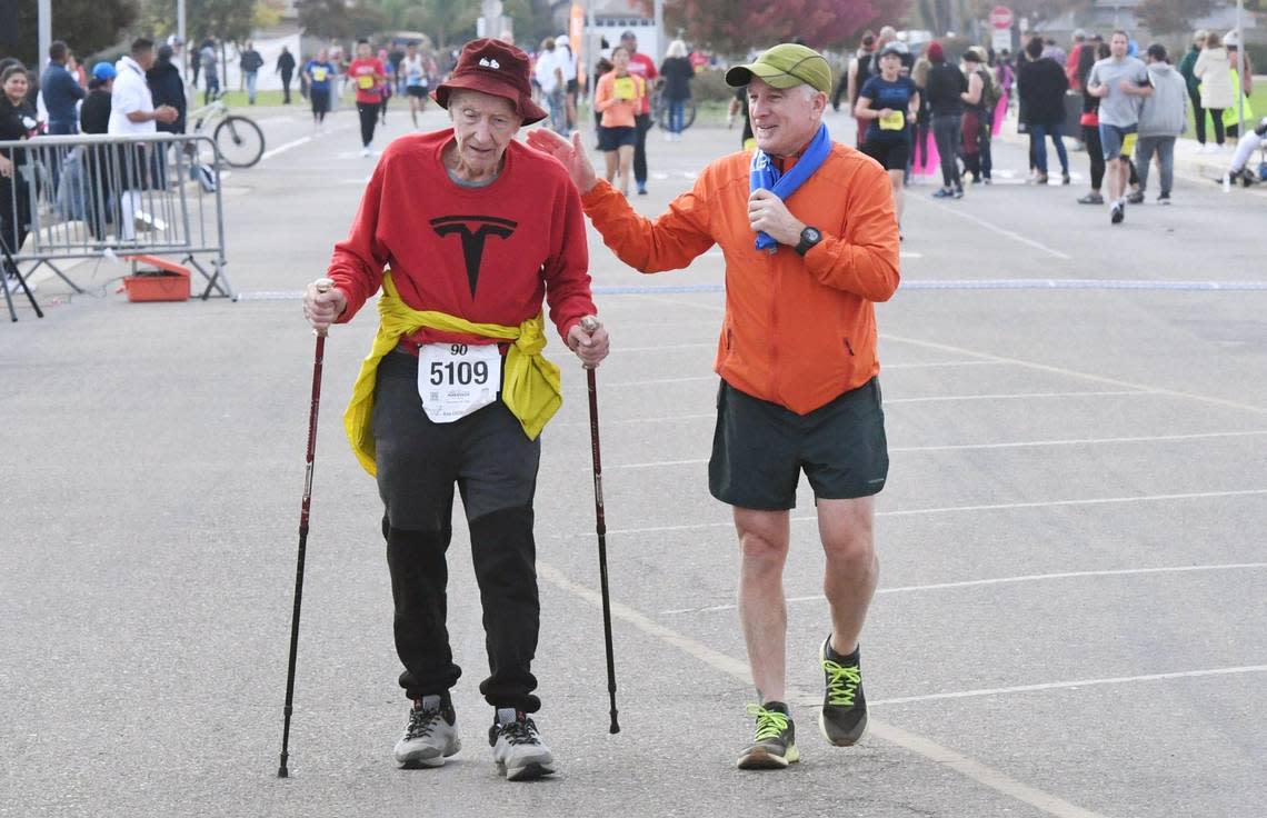 Christopher Denny, 90, of Fresno uses trekking poles as he crosses the finish line in the Gavin Gladding 5K Run/Walk on Sunday, Nov. 6, 2022, in Fresno.