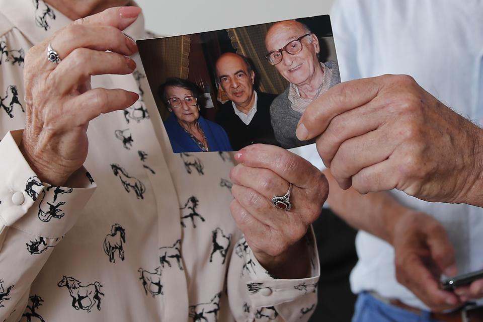 In this photo taken on Friday June 5, 2020, Monette Hayoun, left, shows a photo of her late severely disabled 85-year-old brother, Meyer, center in the picture, flanked with her parents, during an interview in Ivry sur Seine, south of Paris. Families whose elders died behind the closed doors of homes in lockdown are filing wrongful death lawsuits, triggering police investigations. One suit focuses on the death of Meyer Haiun, a severely disabled 85-year-old in a Paris home managed by a Jewish charitable foundation headed Eric de Rothschild, scion of Europe's most famous banking dynasty. (AP Photo/Francois Mori)
