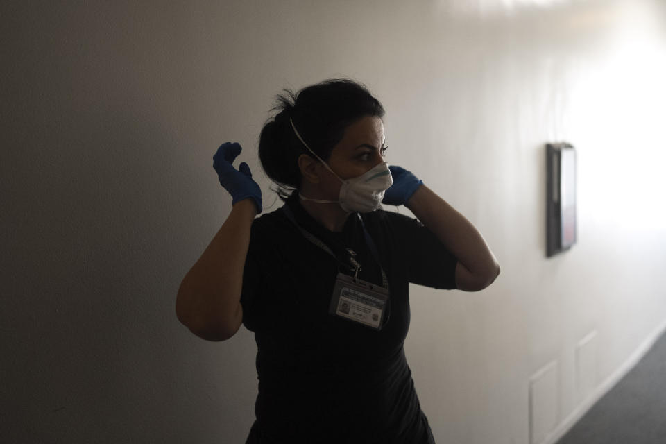 Arusyak Martirosyan, an investigator with the Los Angeles County Public Administrator's office, puts on a protective mask before entering a one-bedroom apartment in Los Angeles, Thursday, Nov. 16, 2023, to search for clues that might lead to finding family members or relatives of a tenant who died in the hospital with no apparent next of kin. (AP Photo/Jae C. Hong)