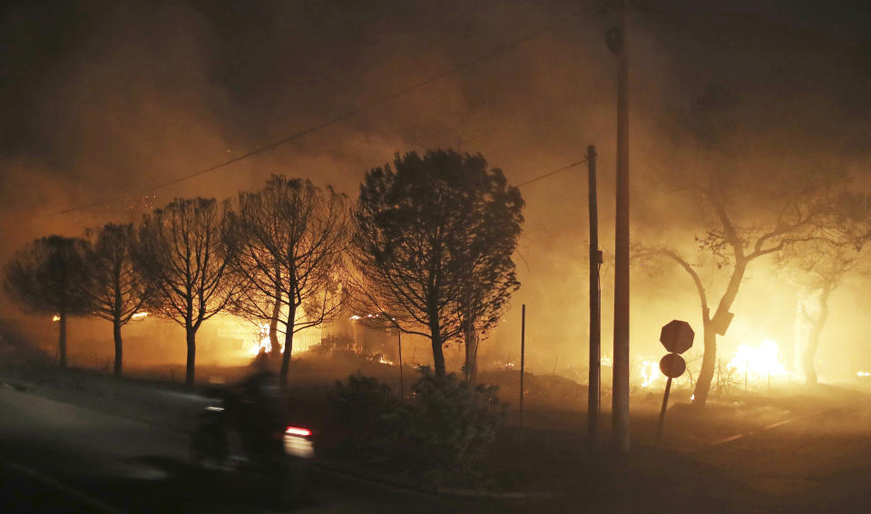 FILE - Buildings burn in the town of Mati, east of Athens, Greece, Monday, July 23, 2018. A court on Monday, April 29, 2024, has convicted five former Fire Service and disaster response officials over a 2018 wildfire outside Athens that killed more than 100 people. (AP Photo/Thanassis Stavrakis, File)