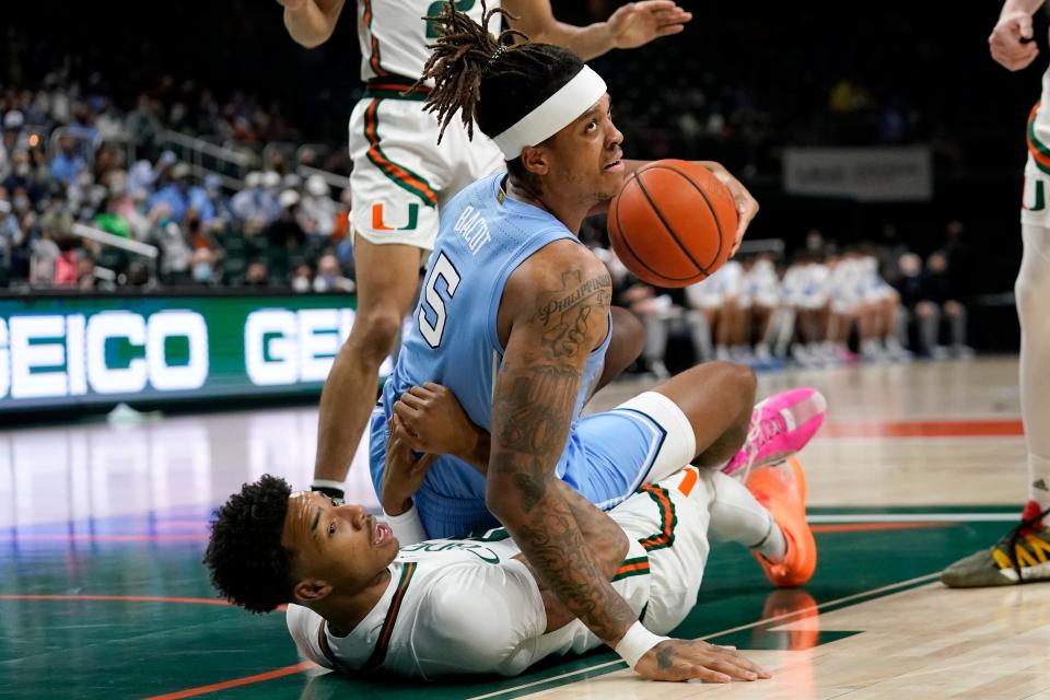 Miami’s Jordan Miller, bottom, draws an offensive foul on North Carolina forward Armando Bacot during Tuesday night’s game.