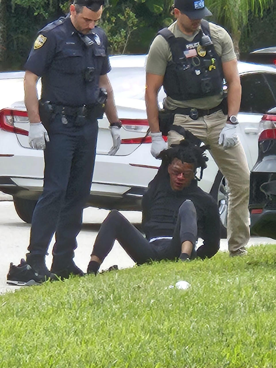 This photo taken from cellphone video provided by Ruby Anderson shows Le’Keian Woods, with swollen eyes and a bloody face sitting on the ground surrounded by officers, as he's taken into custody, Friday, Sept. 29, 2023, in northeast Florida. The Jacksonville Sheriff’s Office was conducting an administrative review of what happened to see if any policies were violated, the agency said in a statement. (Ruby Anderson via AP)