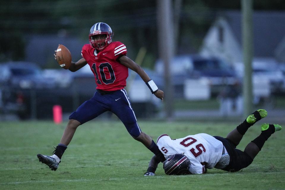 Eastmoor Academy quarterback Stephon Simpkins dodges a sack attempt by Harvest Prep's Rashad Debose on Sept. 2.