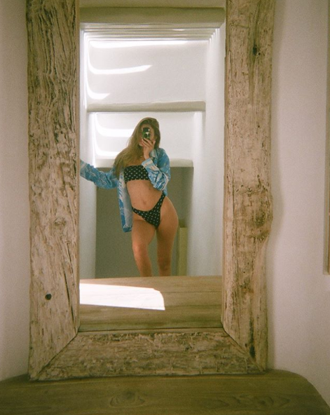 A photo of model Gigi Hadid wearing a black bikini and a blue shirt while posing on holiday in Greece.