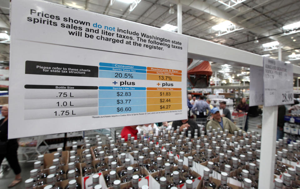 A sign explains the taxes that will be added for liquor customers at check-out at a Costco warehouse store Friday, June 1, 2012, in Seattle. Private retailers begin selling spirits for the first time under a voter-approved initiative kicking the state out of the liquor business. The initiative allows stores larger than 10,000 square feet and some smaller stores to sell hard alcohol.(AP Photo/Elaine Thompson)