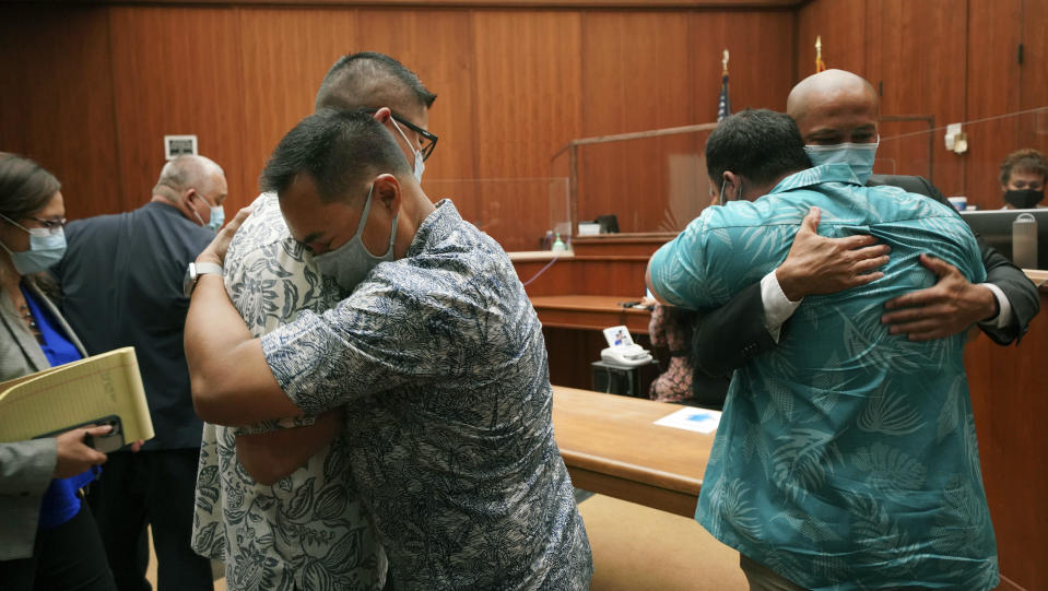 Honolulu Police officers Geoffrey Thom, left, and Christopher Fredeluces embrace as defense attorney Thomas Otake embraces his client Zackary Ah Nee after Judge William Domingo rejected murder and attempted murder charges against the officers in the fatal shooting of a teenager, preventing the case from going to trial, Wednesday, Aug. 18, 2021, at district court in Honolulu. (Cory Lum/Honolulu Civil Beat via AP, Pool)