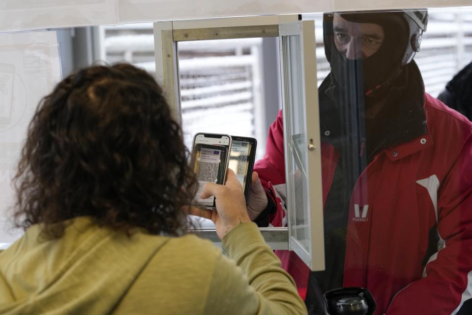 A tourist shows his green pass at the ticket office prior to boarding a gondola in San Vigilio di Marebbe, Italy South Tyrol, Saturday, Nov. 27, 2021. After nearly two years of being restricted to watching snow accumulate on distant mountains, Italian skiers are finally returning to the slopes that have been off limits since the first pandemic lockdown in March 2020. But just as the industry is poised to recover from a lost 2020-2021 season after an abrupt closure the previous year, a spike in cases in the Alpine province bordering Austria is underlining just how precarious the situation remains. (AP Photo/Luca Bruno)