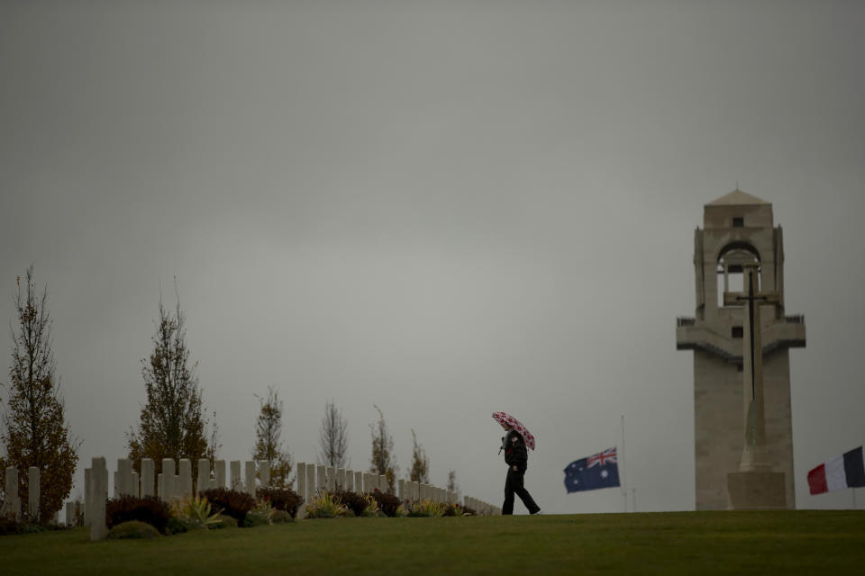 A man walks near headstones at the World War I Australian National Memorial in Villers-Bretonneux, France, Saturday, Nov. 10, 2018. The memorial walls at the site bear the names of 11,000 missing Australian soldiers who died in France during World War I. (AP Photo/Francisco Seco)